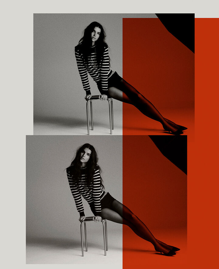 A brunette model sitting on a stool wearing tights, black high heels and a striped knitted jumper. 